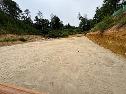 農道側の壁を削りました。横幅が1mほど広くなったと思います。不要になった砂は奥に山積みにされてます。